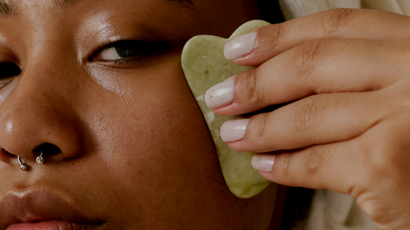 A woman holding a skincare accessories to her face